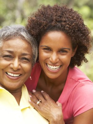 Senior Woman Hugging Adult Daughter In Garden